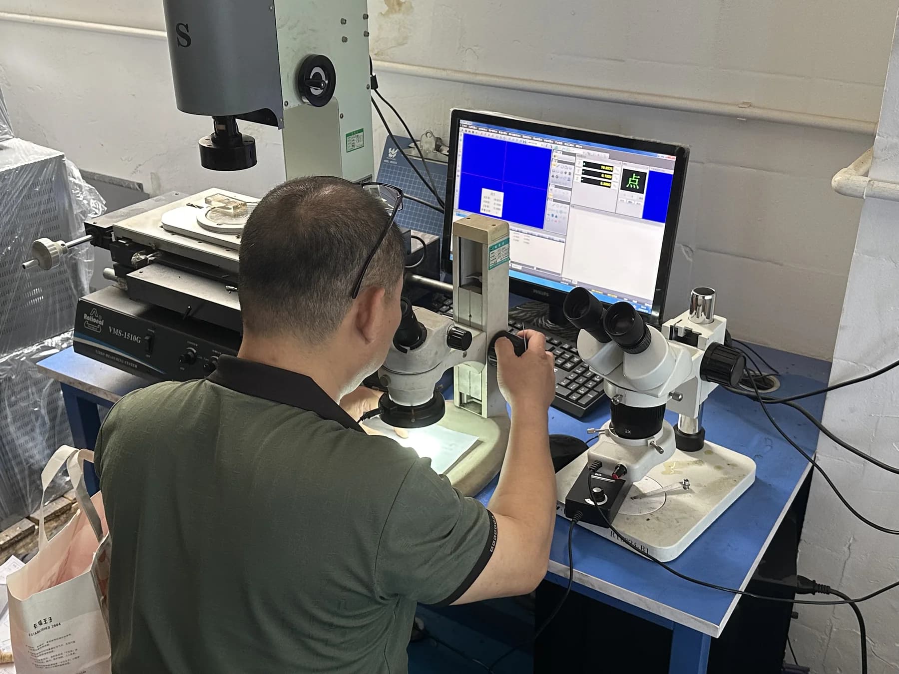 Factory staff inspecting a small component with optical measurement equipment