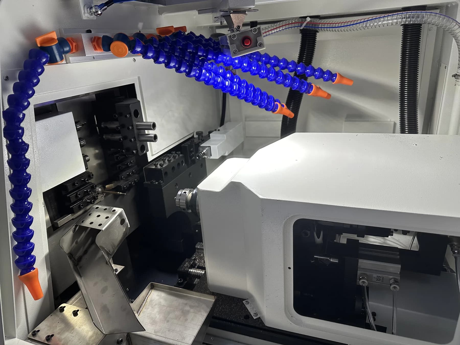 Swiss-type CNC lathe working area with tooling and coolant lines visible